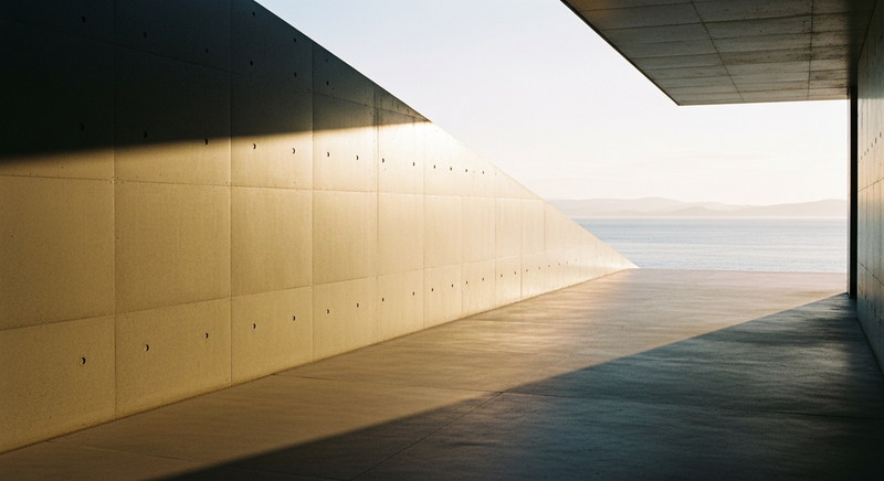 A concrete museum terrace overlooking still water at golden hour, the Seto Inland Sea flat and silver beyond, late summer light on bare stone