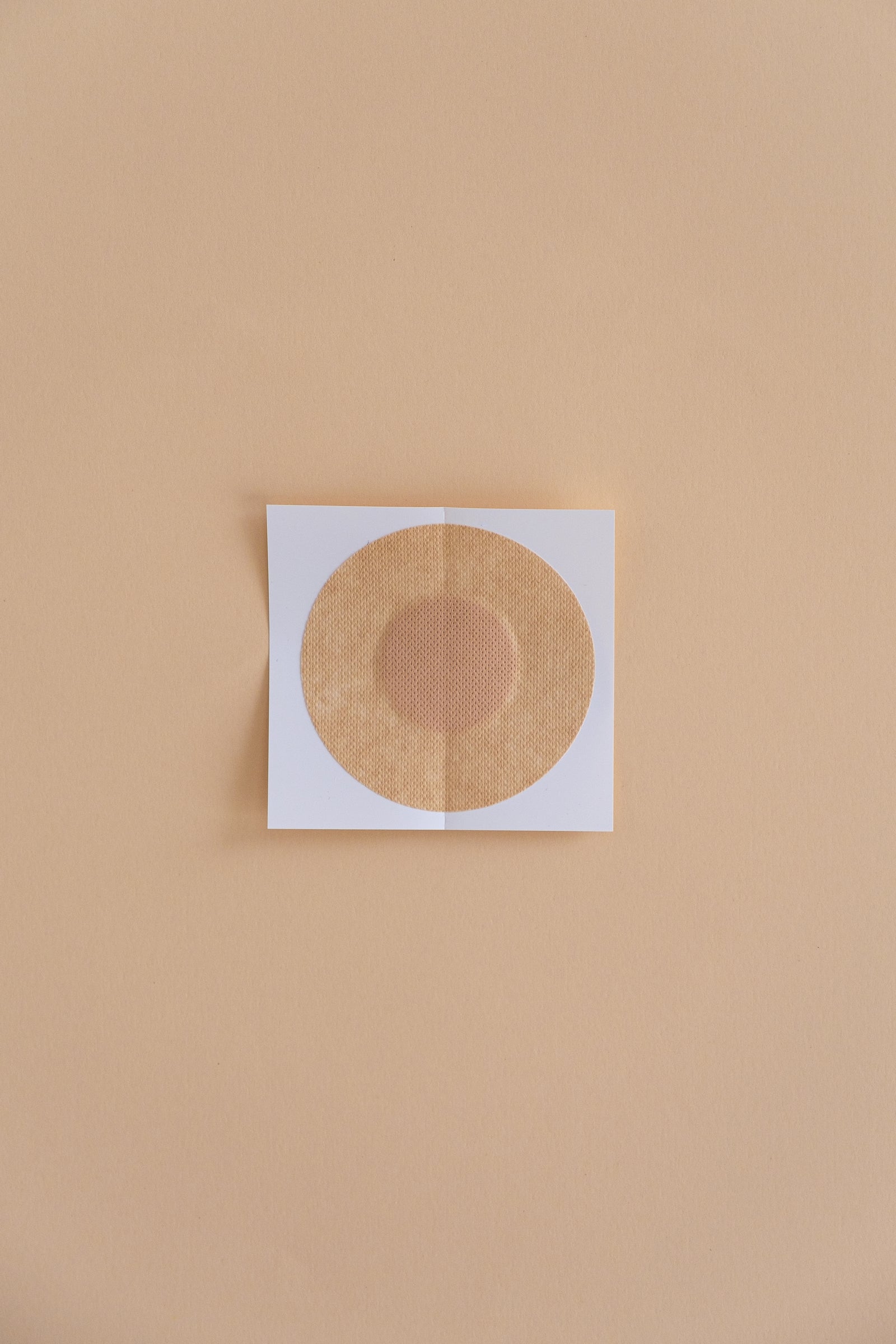 Single-use circle paper nipple cover on parchment background