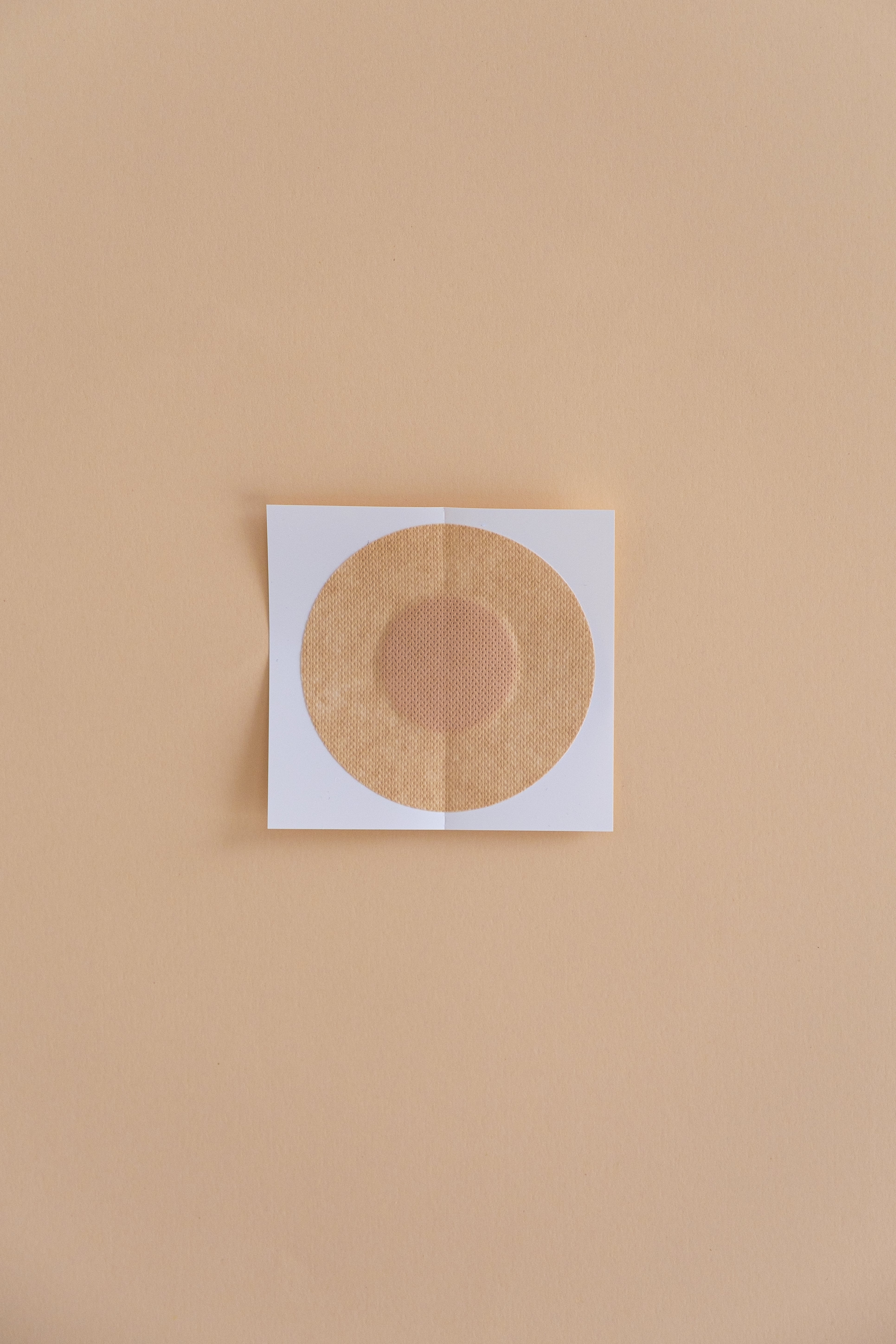 Single-use circle paper nipple cover on parchment background