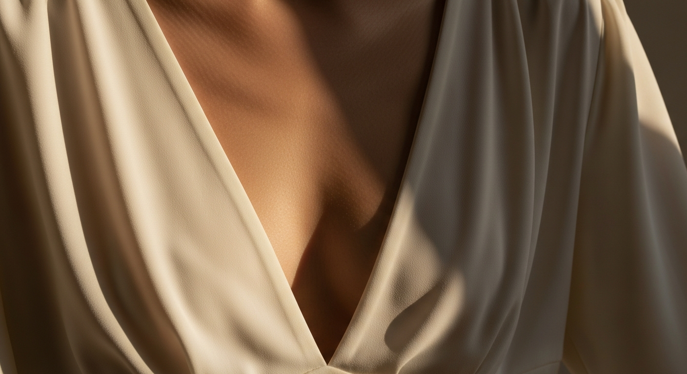 Detail of a deep-v neckline in ivory crepe against warm afternoon light, fabric falling cleanly