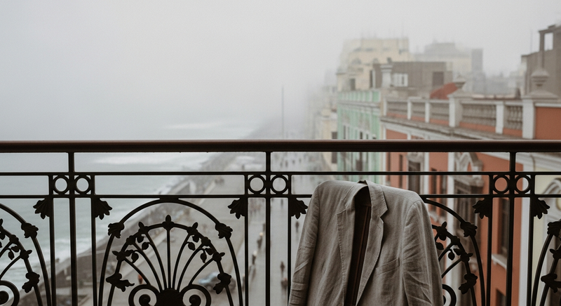 Morning fog diffusing light across a coastal Barranco terrace with a linen jacket draped over an iron chair